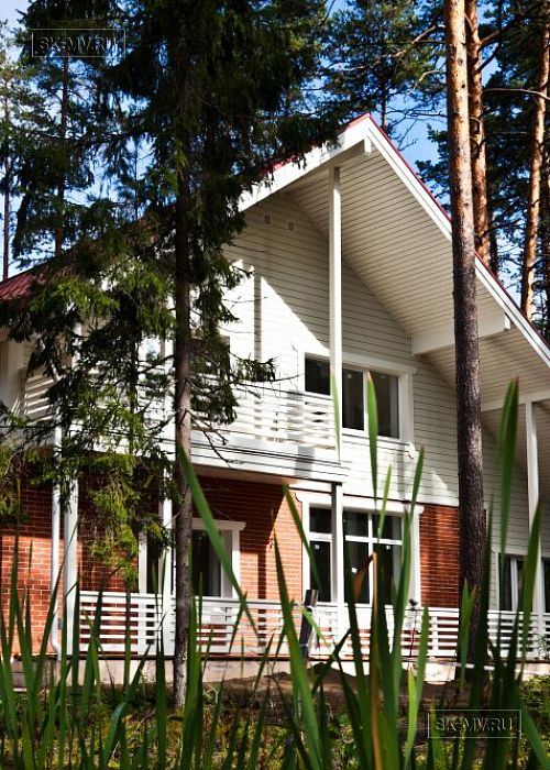 Строительство каркасного коттеджа 220 кв м аля шале с широкими кровельными свесами и остекленной верандой в комбинированной фасадной отделке красным лицевым кирпичом и белым имитатором бруса в п Вырица