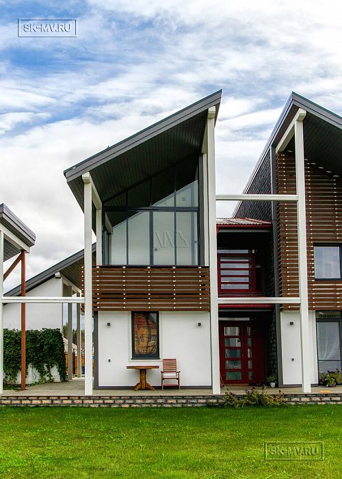 Построенный каркасный дом с навесом для автомобиля, террасой барбекю и навесным фасадом из планкена из лиственницы в КП Сосновое