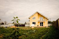 Построенный в с Озерецкое Московской области небольшой каркасный дом 151 кв м с отделкой желтой штукатуркой с балконом и открытой террасой  - мини - 3