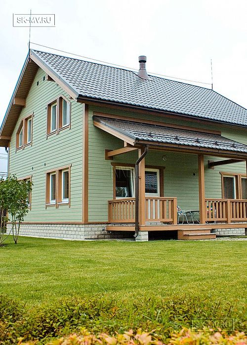 Построенный в п Борисово небольшой двухэтажный каркасный дом 147 кв.м с фасадом из светло зеленой вагонки, сауной, навесом для авто и четырьмя спальнями